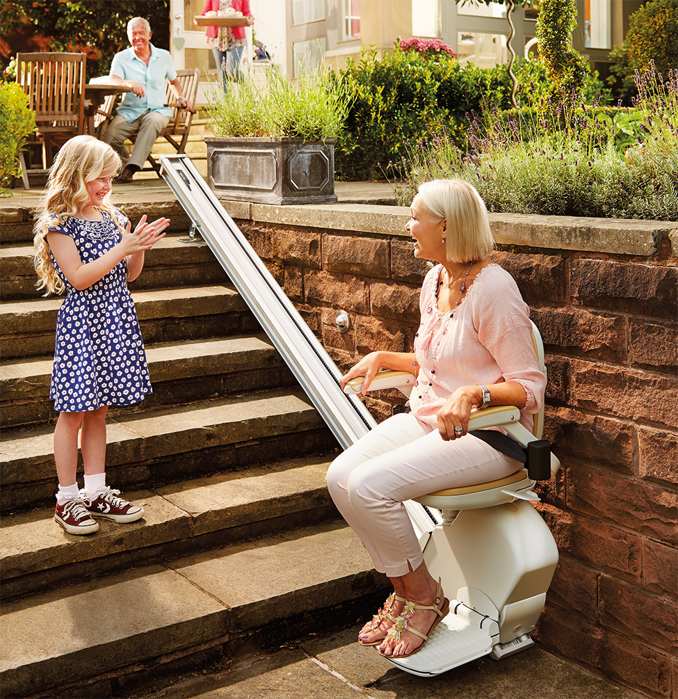 Senhora com criança no exterior a aplaudir a sua utilização da cadeira elevatória exterior
